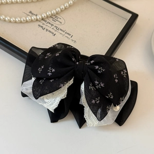 Detail of French mesh lace bow hair clip with floral pattern and delicate layering