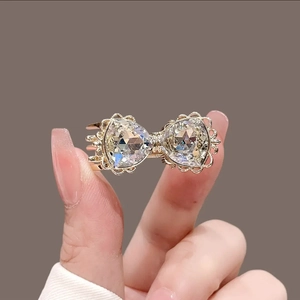 Barrette à cheveux nœud doré élégante avec deux cristaux clairs et détails métalliques fins
