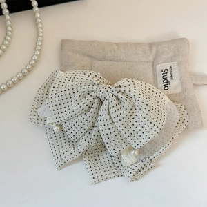 Close-up of layered polka dot bow hair clip with lace edges and small hanging pearls