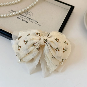 Detail of floral chiffon bow hair claw with lace edges and elegant pearl pendants