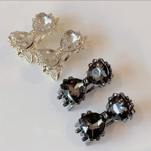 Gros plan de barrettes à nœuds en cristal scintillant, dorées et gris foncé
