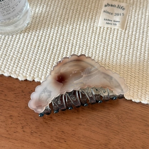 Close-up of a marbled beige shark hair clip with golden Barrette la France text detail