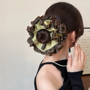 Détail d'un chouchou plissé surdimensionné marron et jaune porté sur un chignon