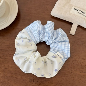 Detail of checkered and floral patchwork scrunchie on a rustic wooden surface