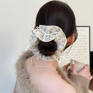 Elastico per capelli floreale con fiocco bianco mostrato in una scena di acconciatura