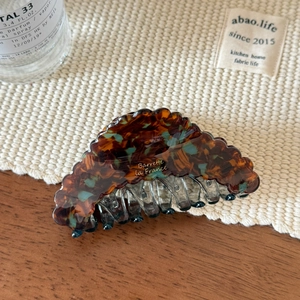 Detail of acetate shark hair claw with tortoiseshell pattern and golden text engraving