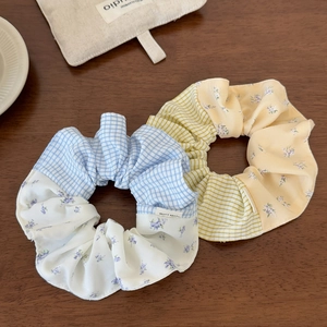 Detail of yellow and blue plaid scrunchies with floral patchwork and handmade label