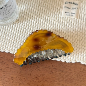 Detail of amber tortoiseshell claw clip with Barrette la France text on white woven mat