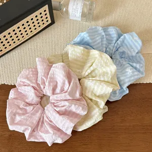 Close-up of three striped pastel scrunchies with bow patterns on a wooden surface