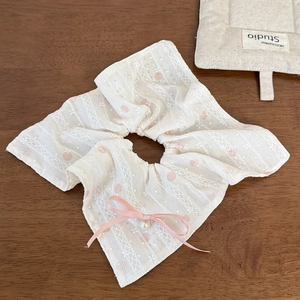 Makroaufnahme von cremefarbenem Spitze-Haargummi mit rosa Punkten, Schleife und Perle