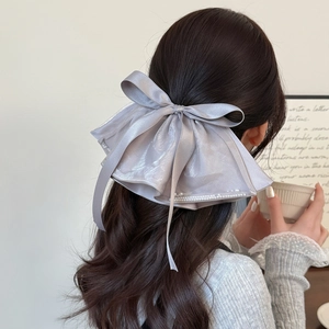 Elegant grey satin bow hair clip with pearl accents shown on model's hairstyle