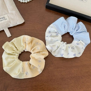 Detailed view of handmade plaid and floral scrunchies set on a rustic wooden background