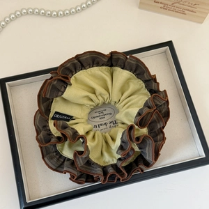 Détail d'un chouchou à froufrous marron et crème avec étiquette Original distinctive