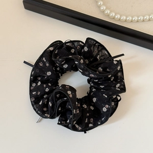 Dettaglio di scrunchie in chiffon a fiori con elegante collana di perle sullo sfondo