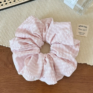 Close-up of a pink and white checkered scrunchie with cute bow and polka dot patterns