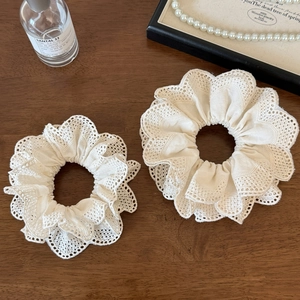 Elegant white lace scrunchie set with delicate ruffles on vintage wood surface
