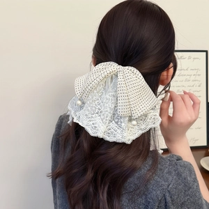Elegant polka dot lace bow hair clip with faux pearls on model wavy brown hair