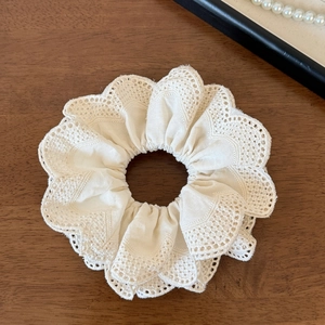 Detailed close-up of multi-layer white lace scrunchie with intricate floral patterns