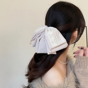 Detail of gingham lace bow hair clip with pearl pendants on a model's hairstyle