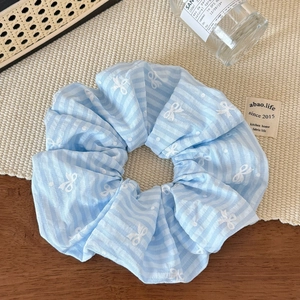 Detailed close-up of light blue striped scrunchie with cute bow and polka dot patterns