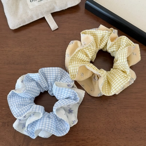 Close-up of yellow and blue plaid scrunchie set with floral patchwork on wooden table