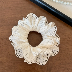 Close-up of white lace fabric texture on tiered scrunchie with scalloped edge detail