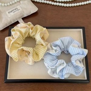 Detail of yellow and blue plaid scrunchies with floral stitching in a display tray