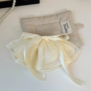 Detail of cream satin bow hair clip with layered organza ruffles and small pearl beads