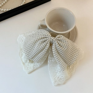 Detail of white mesh lace bow hair clip with black polka dots and pearl accents
