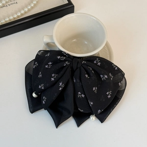 Détail d'une pince à cheveux en tulle noir avec imprimé floral et perles blanches