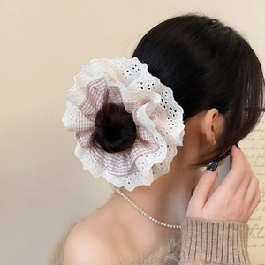 Detail of pink plaid hair scrunchie with white lace embroidery on a high bun