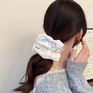 Détail du chouchou en dentelle avec nœud bleu, perle et étiquette fait main brodée