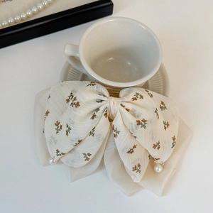 Détail d'un nœud à cheveux en mousseline fleurie avec perles blanches et style français
