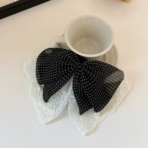 Detail view of polka dot mesh and white floral lace with elegant pearl pendants