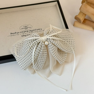 Détail de la pince à cheveux beige à pois en organza avec perle et nœud en ruban