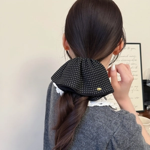 Detail of French polka dot hair claw clip on low ponytail with elegant fabric bow silhouette