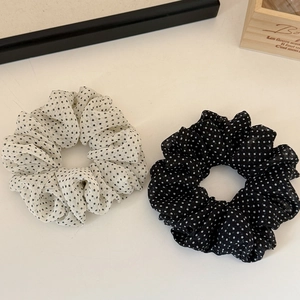 Dettaglio degli elastici per capelli in rete a pois con motivi neri e bianchi a contrasto