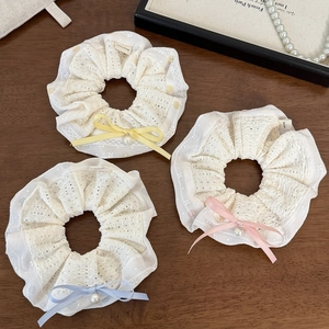 Détail de chouchous en dentelle blanche avec nœuds pastel et pendentifs en perles fines