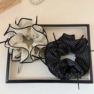 Close-up of black and white polka dot mesh scrunchies with elegant ribbons in a gift box