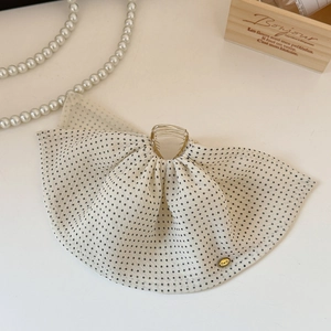 Detail of elegant cream mesh hair claw with black polka dots and gold heart logo charm