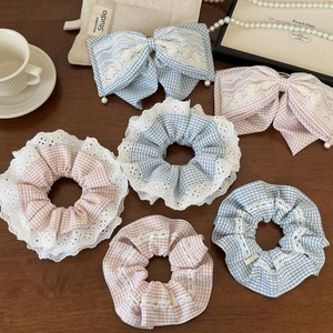 Flat lay of blue and pink plaid hair scrunchies with lace trim on a wooden table