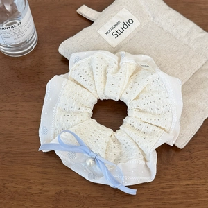 Détail d'un chouchou en dentelle blanche avec nœud bleu et perle décorative