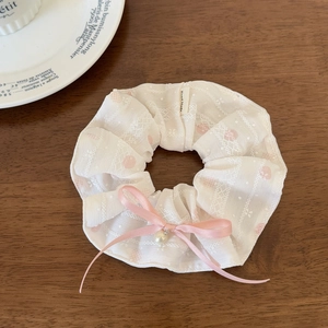 Detail of cream chiffon scrunchie with pink polka dots, lace, and a pearl bow