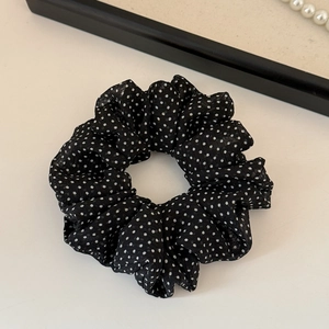 Dettaglio di un elastico per capelli in mesh nero a pois con pieghe e perle bianche