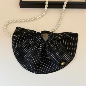 Detailed macro view of black polka dot fabric bow hair claw with gold logo plate