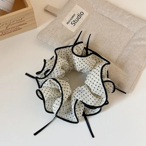 Close-up of black and white polka dot mesh scrunchie with elegant ribbon details