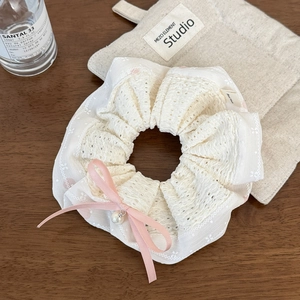 Détail du chouchou en dentelle blanche avec nœud en satin rose et perle pendante