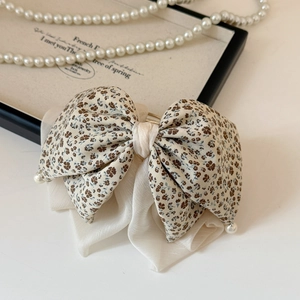 Dettaglio del fermaglio per capelli beige a fiori con strati di chiffon e piccole perle