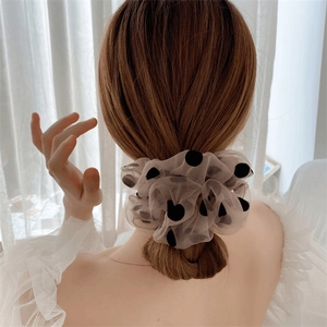 Détail d'un chouchou en maille beige à pois sur un chignon bas sous une lumière naturelle
