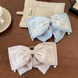 Close-up of pink and blue plaid scrunchies with white floral lace and pearl pendants